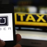 Uber-App, im Hintergrund ein Taxi-Schild