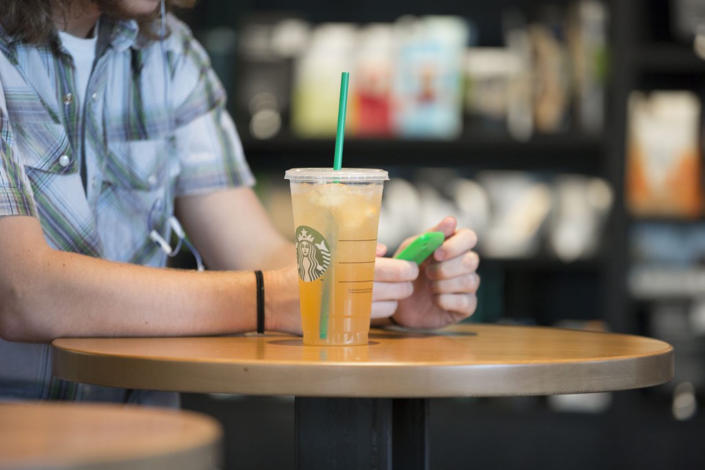 Starbucks Getränk auf einem Tisch mit einer Person, die am Smartphone ist